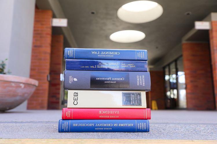 A pile of textbooks sit on the ground outside.