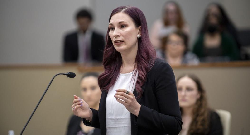 A law student stands at a podium in a courtroom.